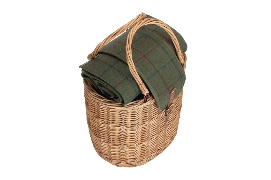 Wicker picnic basket with a green plaid blanket on a white background