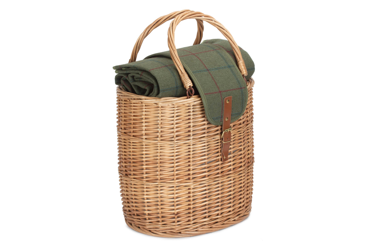 Wicker picnic basket with a green blanket on a white background