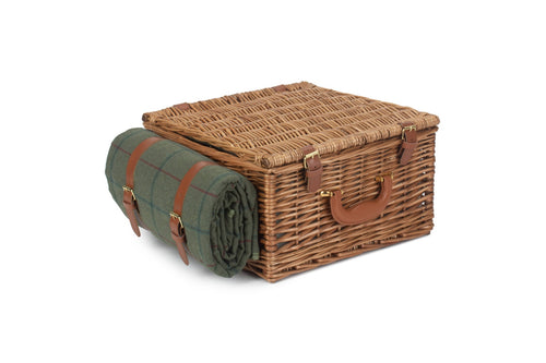 Wicker picnic basket with a green blanket on a white background